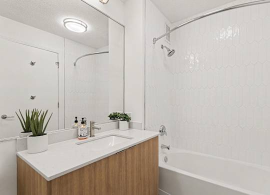A white bathroom with a wooden vanity and a white bathtub.