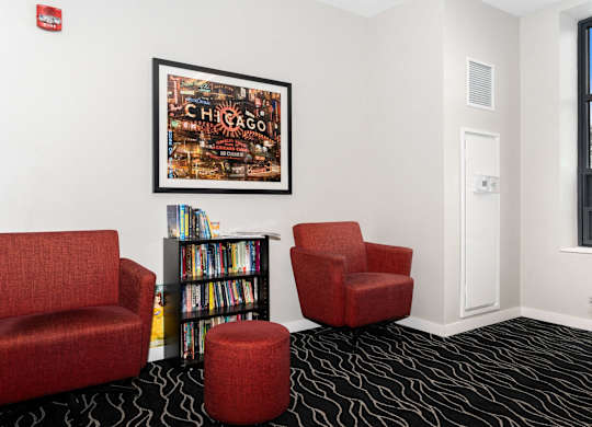 a room with three red chairs and a bookshelf filled with books