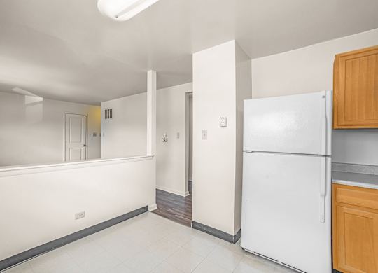 A white refrigerator sits in a kitchen next to a wooden cabinet.