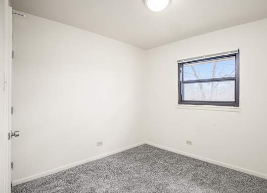 A room with a window and carpeted floor.