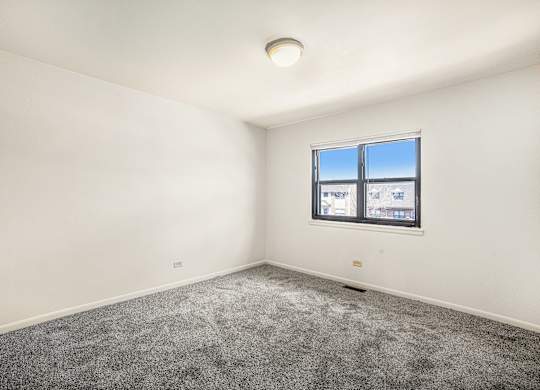 A room with a window and a grey carpet.
