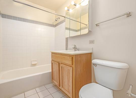 A white toilet sits next to a wooden cabinet in a bathroom.