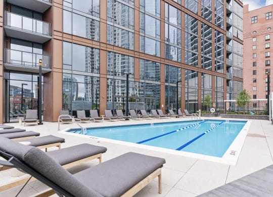 a swimming pool with lounge chairs in front of a tall building at Cassidy on Canal, Chicago, IL, 60606