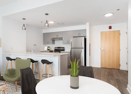 A modern kitchen with a white table and bar stools.