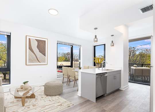 A modern kitchen with a white countertop and wooden chairs.