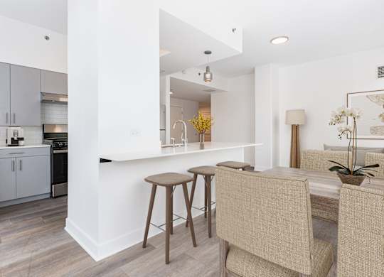 A kitchen with a bar area and a dining table with chairs.