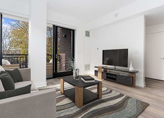 A modern living room with a grey sofa, a black coffee table, and a flat screen TV.