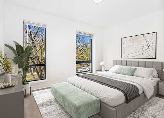 A bedroom with a large bed and a window overlooking a tree.