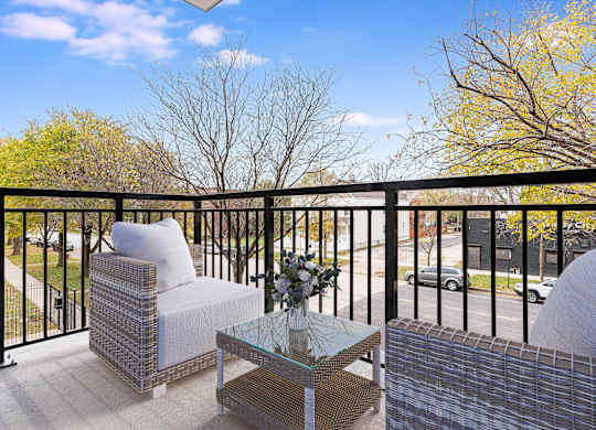 A balcony with a chair, table and flowers.