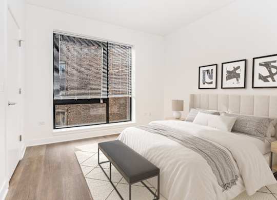 A bedroom with a large bed and a window with blinds.