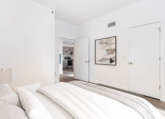 A bedroom with a large bed and a picture on the wall.