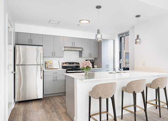 A kitchen with a white island and bar stools.