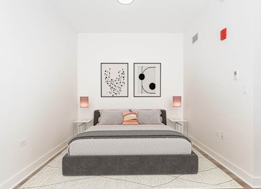 A bedroom with a bed, two lamps, and two framed artworks on the wall.