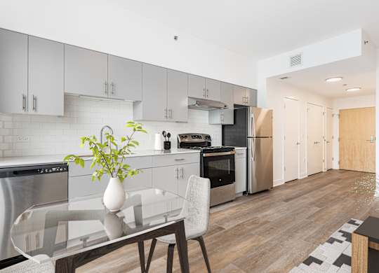 A modern kitchen with a glass table and a plant on it.