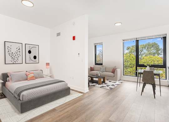 A bedroom with a large bed and a chair in front of a window.