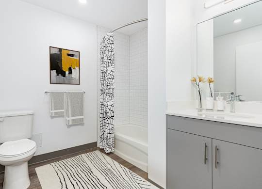 A bathroom with a toilet, sink, and a painting on the wall.