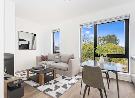 A modern living room with a large window overlooking a tree-filled yard.