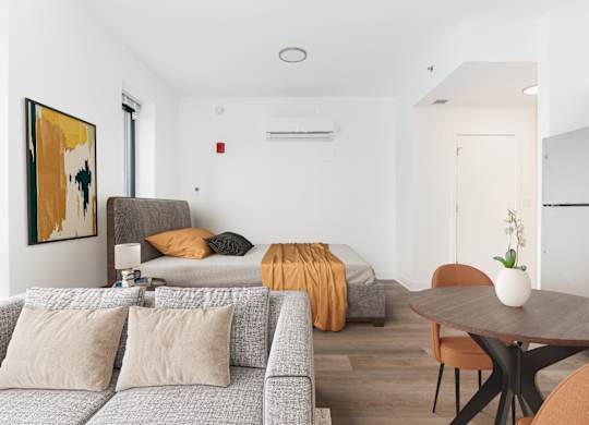 A living room with a grey couch and a painting on the wall.