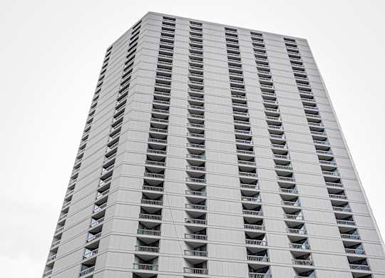 A tall building with a grey facade and balconies on the upper floors.