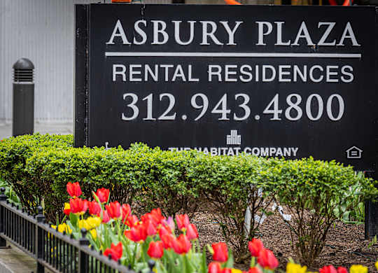 A sign for Asbury Plaza Rental Residences with a phone number and a small house icon.
