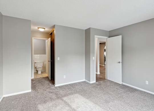 Empty bedroom with carpet and bathroom access at Cedarvale Highlands Apartments, Eagan