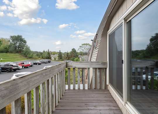 Apartment balcony with wooden railings overlooking parking at Cedarvale Highlands Apartments, Minnesota