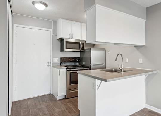 Compact kitchen with breakfast bar and modern appliances at Cedarvale Highlands Apartments, Eagan, MN