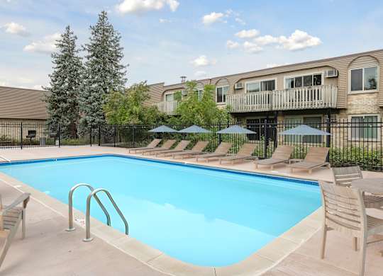 Swimming pool with lounge chairs and umbrellas1 at Cedarvale Highlands Apartments, Eagan, MN 55122