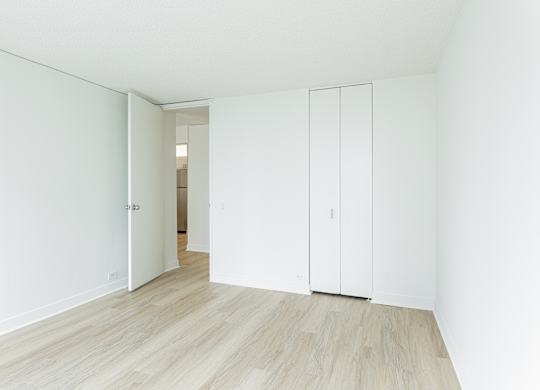 A white room with a wooden floor and a white door at Columbus Plaza, Chicago, Illinois