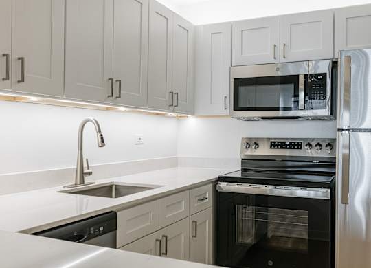 A modern kitchen with a stainless steel refrigerator, oven, and microwave at Columbus Plaza, Chicago, 60601