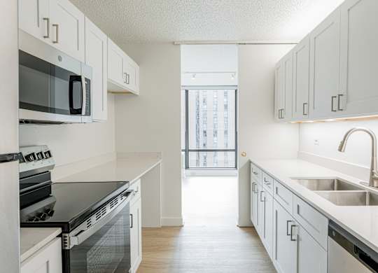 A kitchen with white cabinets and black appliances at Columbus Plaza, Chicago, Illinois