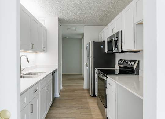 A kitchen with white cabinets and black appliances at Columbus Plaza, Chicago, 60601