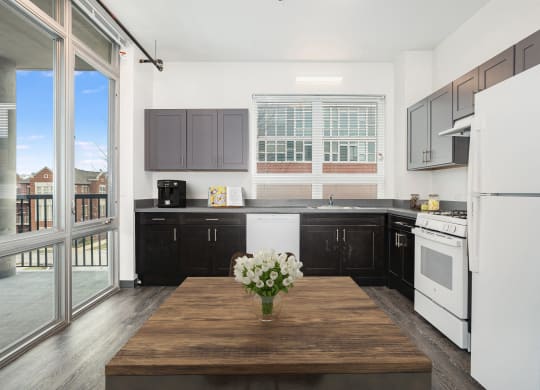 a kitchen with black cabinets and white appliances and a wooden table
