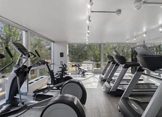 a gym with treadmills and other cardio equipment in a building with large windows at The Pavilion, Michigan, 48207
