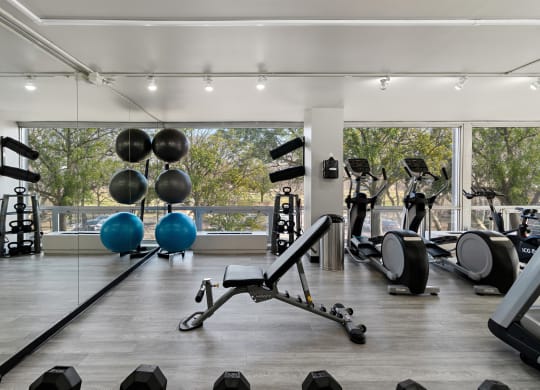 a gym with weights and cardio equipment and a large window at The Pavilion, Detroit