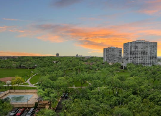 an aerial view of a park with buildings in the background and a colorful sunset in the sky at The Pavilion, Detroit, MI, 48207