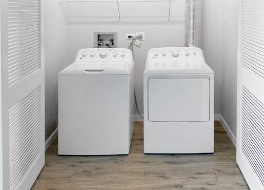 two washing machines in a laundry room with a wood floor
