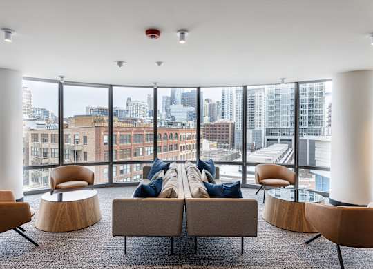 A modern living room with a view of the cityscape outside the large windows at Kingsbury Plaza, Chicago, IL