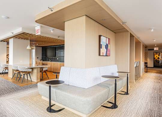 A white couch with a black metal base sits in a room with a wooden ceiling and a painting hanging on the wall at Kingsbury Plaza, Chicago, 60654