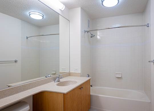 A white bathroom with a sink, mirror, and bathtub.