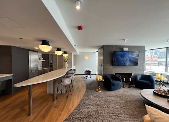 A modern living room with a curved wooden table and a television mounted on the wall at Kingsbury Plaza, Chicago