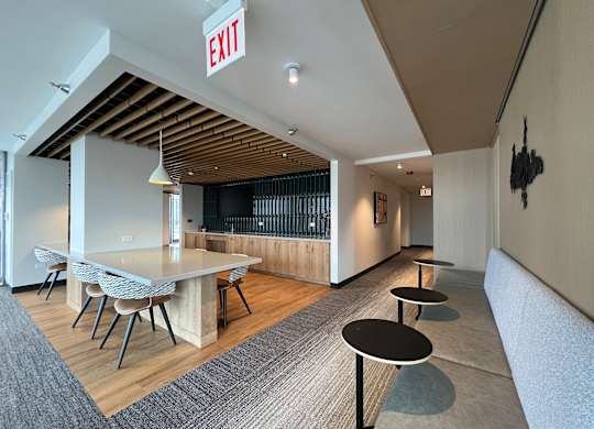 A room with a long table and chairs, a couch, and an exit sign at Kingsbury Plaza, Chicago, IL, 60654