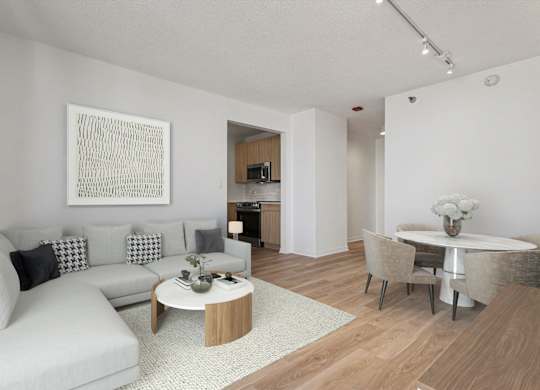 A modern living room with a grey sofa, a coffee table, and a dining table set up.