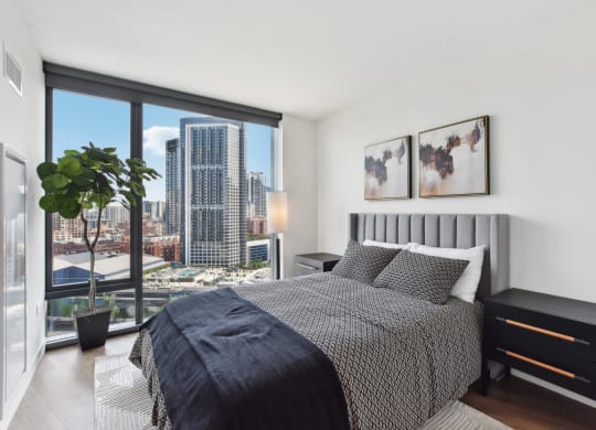 a bedroom with a bed and a large window and a view of the city at Cassidy on Canal, Chicago, IL