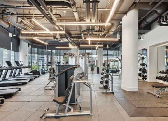 a gym with weights and other exercise equipment in a building with large windows at Cassidy on Canal, Chicago