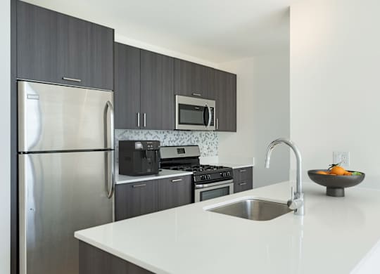 A modern kitchen with a stainless steel refrigerator and a white countertop.