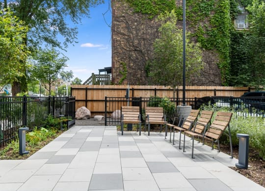 a courtyard with benches and a black fence and a building
