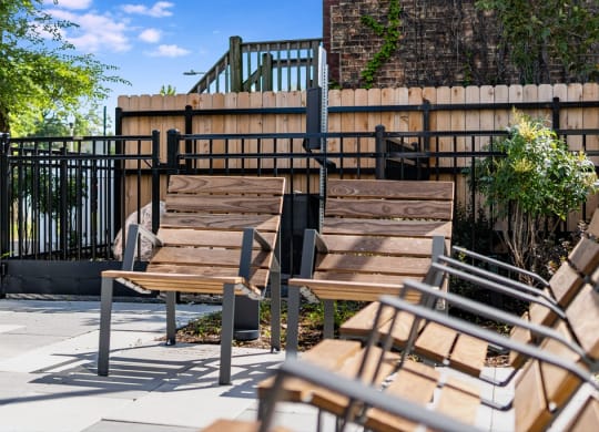 two wooden benches sitting next to a fence