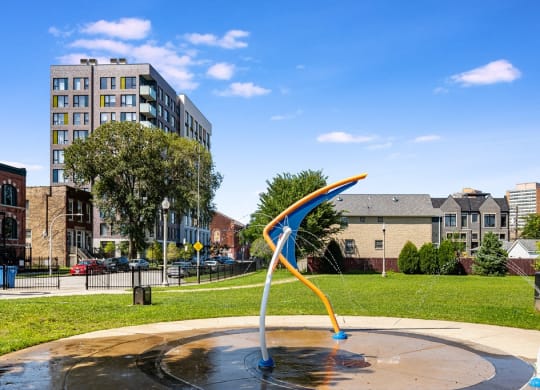 a fountain in a park with buildings in the background