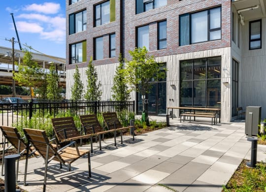 a courtyard with benches and chairs in front of a building